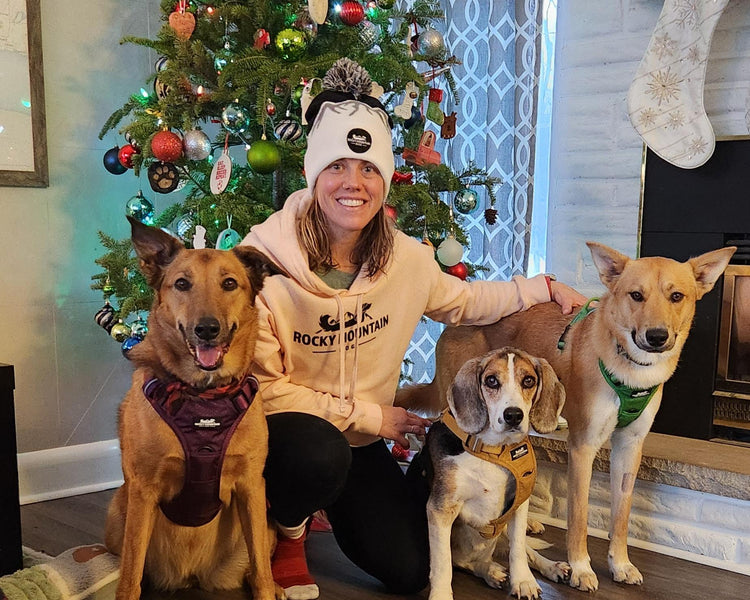 Woman with three dogs in front of a decorated Christmas tree wearing Rocky Mountain Dog products